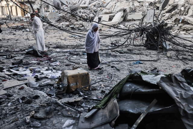 Palestinians walk after performing Eid al-Fitr prayers amidst debris near the al-Sharouk tower, which housed the bureau of the Al-Aqsa television channel in the Hamas-controlled Gaza Strip, after it was destroyed by an Israeli air strike, in Gaza City, on May 13, 2021. Israel faced an escalating conflict on two fronts, scrambling to quell riots between Arabs and Jews on its own streets after days of exchanging deadly fire with Palestinian militants in Gaza. © Mohammed Abed / AFP